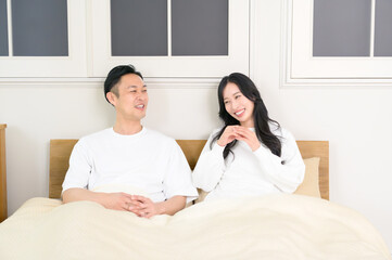 夜の寝室で笑顔で会話をする日本人男女