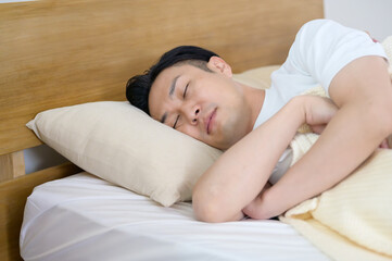 寝室のベッドで横向きに眠る日本人男性