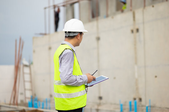 inspection, Asian Man working, Architect or contractor working on house building under construction. Professional Architects Engineer construction site. Civil Engineering in safety harthat helmet - Powered by Adobe