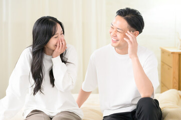 夜の寝室で笑顔で会話をする日本人男女