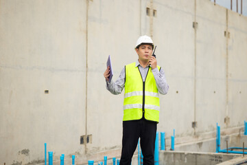 walkie talkie, Asian Man working, Architect or contractor working on house building under construction. Professional Architects Engineer construction site. Civil Engineering in safety harthat helmet