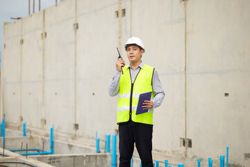 walkie talkie, Asian Man working, Architect or contractor working on house building under construction. Professional Architects Engineer construction site. Civil Engineering in safety harthat helmet