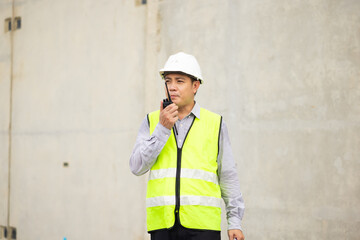 walkie talkie, Asian Man working, Architect or contractor working on house building under construction. Professional Architects Engineer construction site. Civil Engineering in safety harthat helmet