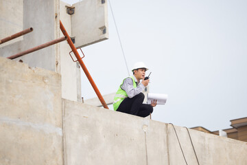 walkie talkie, Asian Man working, Architect or contractor working on house building under construction. Professional Architects Engineer construction site. Civil Engineering in safety harthat helmet