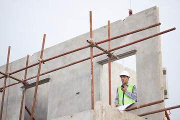 walkie talkie, Asian Man working, Architect or contractor working on house building under construction. Professional Architects Engineer construction site. Civil Engineering in safety harthat helmet