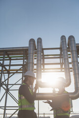 Industrial engineers collaborating on technical project at refinery plant, project management and modern construction technology, Oil and Gas Petrochemical industry.