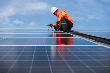 Technician installing solar panels on factory roof for green energy. A skilled technician in safety gear is working on a solar panel installation on rooftop.