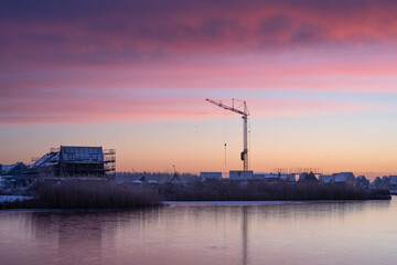 A crane at a construction site during a colourful, winter sunrise. Meerstad, the Netherlands.