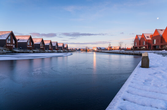A colourful, winter sunrise in modern neighbourhood at the waterfront. Meerstad, the Netherlands.