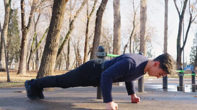 Strong man doing push ups on parallel bars outside.