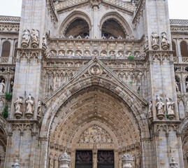 Detailed view of the intricate stone carvings and religious statues on the facade of the historic Toledo Cathedral in Spain.