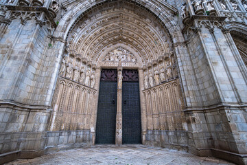 Intricate stone carvings and sculptures decorate the grand arched entrance of the historic Toledo Cathedral in Spain.