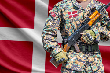 Denmark flag with soldier in military uniform holding assault rifle in front of it