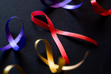 Red ribbon on a black background symbolizes World Cancer Day on February 4th. Additional ribbons in...