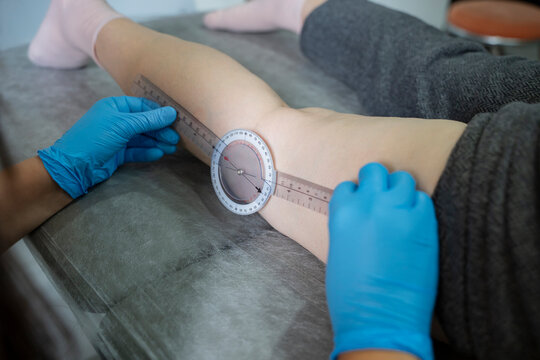 The physiotherapist is measuring the patient's leg angle with a goniometer. (stock photo)