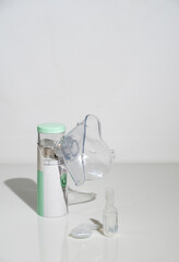 Nebulizer for inhalation and bottles with medicine on a white background, space for text.