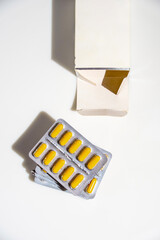 Yellow pills spilling out of a box on a white background, mockup.