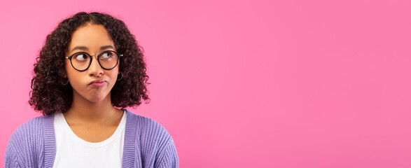 A girl with curly hair looks thoughtfully to the side. She wears glasses and a purple sweater. The background is pink, adding a bright contrast. Her expression suggests she is pondering something.