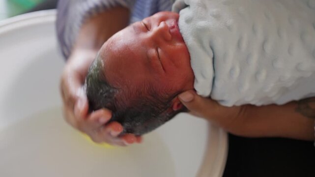 Close-up of newborn baby crying during bath, showing sensitivity and need for gentle baby care.