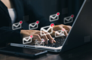 A business professional typing on a laptop with floating email notification icons, symbolizing online messaging, email alerts, digital communication, and modern information technology systems.