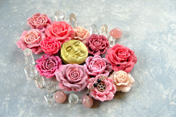 moon amulet, crystals, artificial pink red rose flowers on grey background close up. Magic, esoteric spiritual ritual with gemstones and moon symbol. witchcraft for attracting Love, romantic vibes