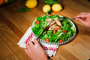 woman eating chicken salad with green lettuce, grilled chicken meat, green peas, lemons, fresh natural healthy mediterranean meal