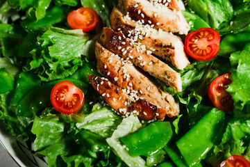 healthy chicken salad with lettuce, green peas, cherry tomatoes, olive oil dressing, close up