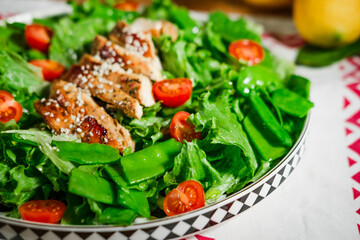 healthy chicken salad with lettuce, green peas, cherry tomatoes, olive oil dressing, close up