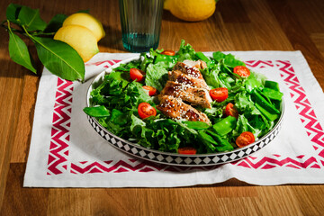 mediterranean styled salad with green lettuce leaves, peas, grilled chicken meat, cherry tomatoes, dressed with olive oil, served for one