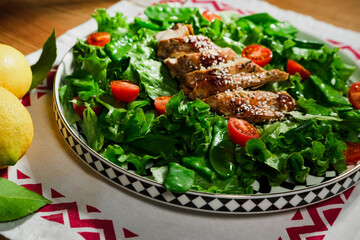 mediterranean styled salad with green lettuce leaves, peas, grilled chicken meat, cherry tomatoes, dressed with olive oil, served for one