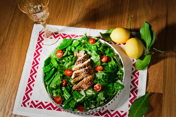 mediterranean styled salad with green lettuce leaves, peas, grilled chicken meat, cherry tomatoes, dressed with olive oil, served for one