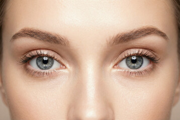 Obraz premium Close-up of a young Caucasian woman with striking blue eyes and natural makeup, showcasing her flawless skin and well-groomed brows. Cosmetic concept