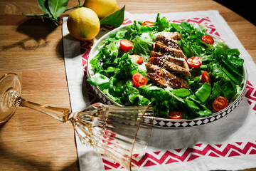 mediterranean styled salad with green lettuce leaves, peas, grilled chicken meat, cherry tomatoes, dressed with olive oil, served for one