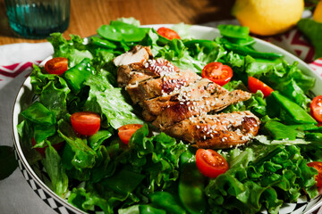 grilled chicken salad with green lettuce, grilled meat, green peas, tomatoes, lemons, fresh natural healthy mediterranean styled meal
