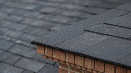 Close-up of roofing shingles and brickwork on a building's roof.