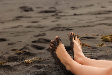 Close up lifestyle photo of bare feet resting on wet sand by the waterline.