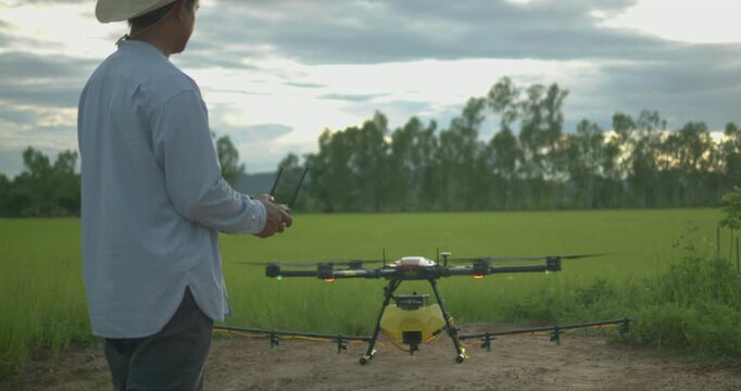 Smart farmer using drone controller or drone transmitter a remote control for agriculture sprayer drone in rice paddy field in rural area countryside farm landscape