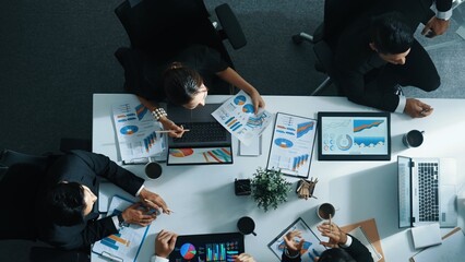 Top down aerial view of skilled businessman pointing financial chart at whiteboard while smart investor listening presentation and analyze stock market investment graph at meeting table. Directorate.