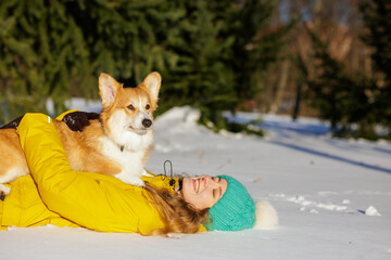 Playful corgi standing on smiling woman in snowy park winter pet bonding