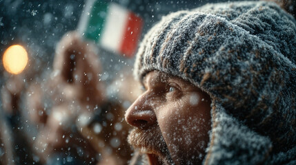 Energetic winter sports fan shouting with raised hands holding blurred Italian flag under bright stadium lights and falling snow 2026 Milano Cortina crowd celebration
