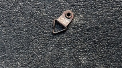 Small metal triangle ring picture hanger on black textured background