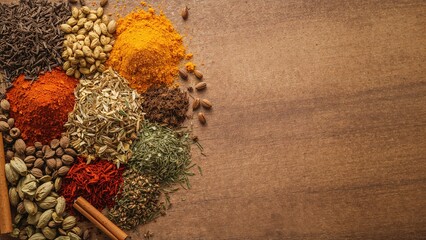 Assorted spices and herbs on a wooden surface, with a blank space on the right side. Culinary, flavoring, and seasoning ingredients. The concept of cooking and gastronomy.