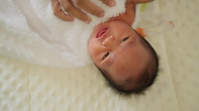 Close-up of a newborn baby wrapped in a white towel after bath, showing a peaceful facial expression. Ideal for baby care, hygiene, and early bonding themes.