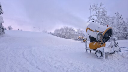 ski lift in the snow, A machine stands in a snowy field surrounded by trees. It is covered in fresh snow, indicating recent weather. The scene shows a winter setting in a rural area.