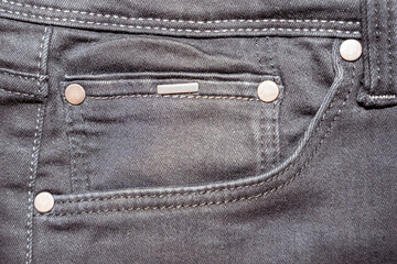 Close-up of a dark denim pocket showcasing metal buttons and stitching details. Ideal for fashion, textile industry studies, and advertising campaigns focused on clothing.