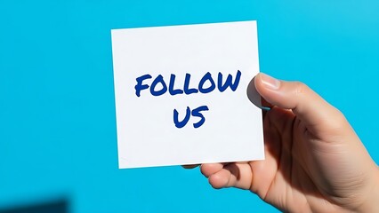 A hand holds a sticky note with the words "FOLLOW US" written in blue marker against a bright blue background, encouraging engagement