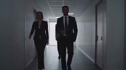 Business professionals walking down a hallway in a corporate building discussing future plans