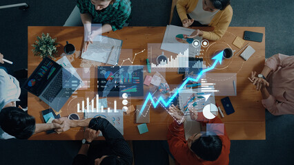 A diverse group of professionals engages in a dynamic meeting, analyzing data on charts and graphs to strategize for business growth in a modern office setting. Scalp