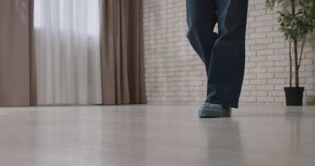 Close up of a woman walking across a wet floor indoors, wearing disposable medical shoe covers for hygiene and safety reasons. Slow motion.