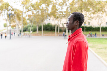 African man standing outdoors in city park, enjoying lifestyle and urban environment